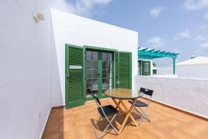 a table and chairs on a balcony with green shutters at Casa Moure in Costa Teguise