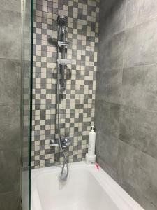 a bath tub with a shower in a bathroom at Ramble Stay Hostel Burj Khalifa view in Dubai