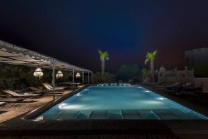 El Arba的住宿－Riad des 1001 Fleurs，游泳池,晚上配有椅子和棕榈树