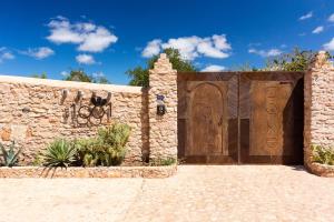 drewniana brama w kamiennej ścianie z podjazdem w obiekcie Riad des 1001 Fleurs w mieście El Arba
