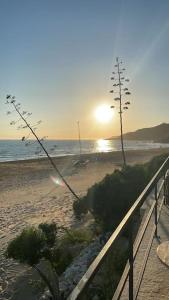 een zonsondergang op een strand met een hek en de oceaan bij Le Stanze della Valle Affitti uso turistico in Agrigento