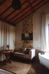 a living room with a couch and a tv on the wall at Bangalô de Pedras in São Thomé das Letras