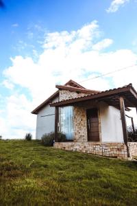 a small brick house on a grassy field at Bangalô de Pedras in São Thomé das Letras