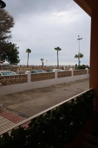 a white fence with palm trees in a parking lot at Apartamento Ve&Va in Torre del Mar