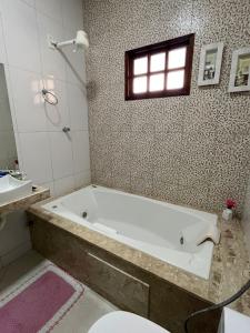 a bathroom with a tub and a toilet and a sink at Casa Confort in Juazeiro do Norte