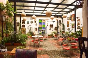 eine Terrasse mit Tischen, Stühlen und Pflanzen in der Unterkunft Hotel Casa de la Luz in Bogotá