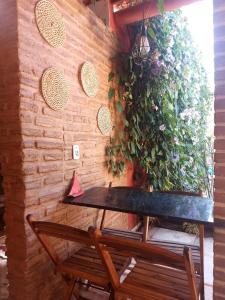 a table and bench next to a wall with plants at Casa Boa Venttura Alugueis - Casa com ar e piscina ou Quartos com ar e cozinha Guajiru Trairi in Trairi +14 photos