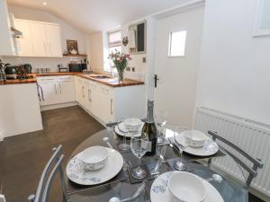 a kitchen with a table with plates and wine glasses at 1 Countryman Inn Cottages in Hunton