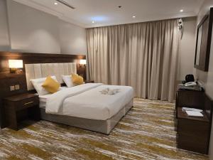 una camera da letto con un grande letto bianco con cuscini gialli di سحابة الأحلام - Dream Cloud Hotel a Gedda