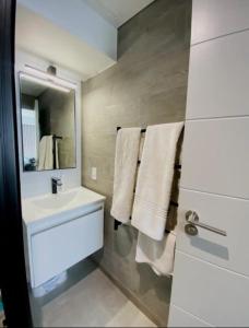 a bathroom with a sink and a mirror and towels at WINK Hotel- Next to CTICC & Best Tourist Location in Cape Town