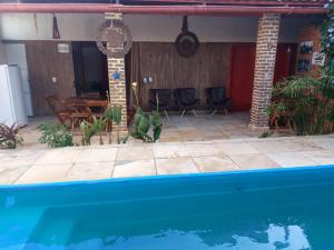 a house with a swimming pool and a table and chairs at Casa Boa Venttura Alugueis - Casa com ar e piscina ou Quartos com ar e cozinha Guajiru Trairi in Trairi