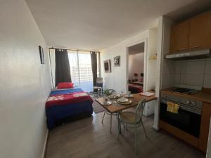 Habitación pequeña con cama, mesa y cocina en Apartment Relocation San Isidro, en Santiago