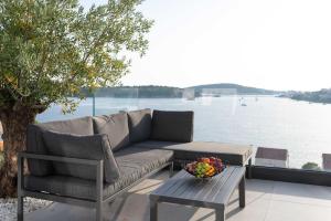 a couch and a table with a bowl of fruit on a patio at Villa Laganini in Rogoznica