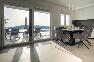a dining room with a table and chairs with a view at Villa Laganini in Rogoznica