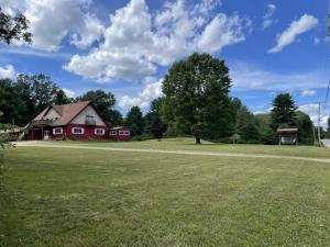 a red barn on a grassy field with a tree at Sweet Forest Breeze, A Cook Forest Inn in Marienville