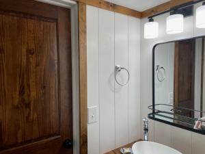 a bathroom with a wooden door and a sink and a mirror at Sweet Forest Breeze, A Cook Forest Inn in Marienville