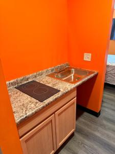 cocina con fregadero y pared de color naranja en Budget Inn Decatur Priceville, en Decatur