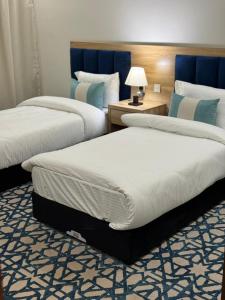 een hotelkamer met 2 bedden en een lamp bij ضيف بارك للأجنحة الفندقية in Dawadmi