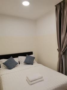 um quarto com uma cama branca e almofadas azuis em Jom Summer Suite - Sutera Avenue em Kota Kinabalu