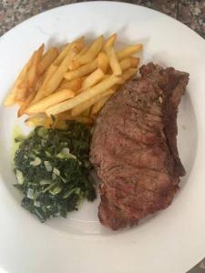 um prato de carne e batatas fritas e verduras em Hospedaria Restaurante Xeque Mate em Luanda