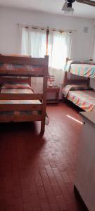 Camera con 3 letti a castello e pavimento piastrellato rosso. di Hostería Vecchia Costa a San Bernardo
