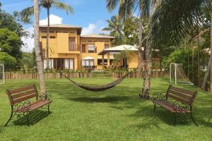 due panchine con un'amaca davanti a una casa di Casa de Luxo Costa do Sauipe a Mata de Sao Joao