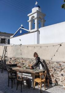 Una donna seduta a un tavolo di fronte a un palazzo di Onos Eco Living a Mési