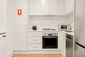 雪梨的住宿－City Centre Studio by Hyde Park，白色的厨房配有炉灶和微波炉。