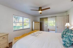 1 dormitorio con cama blanca y ventilador de techo en The Wicker Wonder en Lake Placid