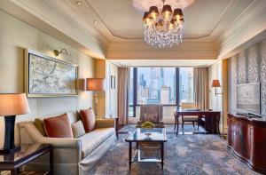a living room with a couch and a table with a piano at Waldorf Astoria Shanghai on the Bund in Shanghai