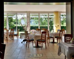 a dining room with tables and chairs and windows at Hotel Italia in Monfalcone