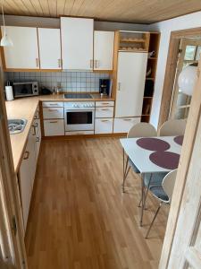 a kitchen with white cabinets and a table with chairs at Søbugten in Nykøbing Mors