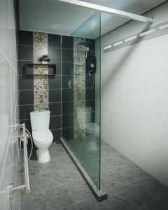 La salle de bains est pourvue de toilettes et d'une douche en verre. dans l'établissement Pondok Beach Shack, à l'Île Tioman