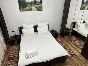 una camera da letto con letto, lenzuola e cuscini bianchi di Vila Agata a Sinaia