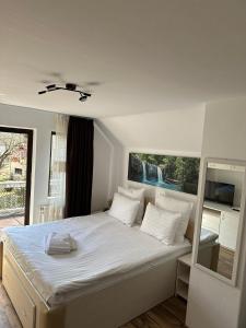una camera da letto con un grande letto con lenzuola e cuscini bianchi di Vila Agata a Sinaia
