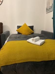 Una cama amarilla con dos toallas encima. en Ocean Home stay en Colchester