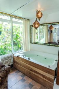 a bath tub in a room with a large window at Spa Hosteria Miramelindo in Baños