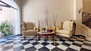 two chairs and a table in a room with a checkered floor at Casa Lucia Hotel Boutique in Mérida