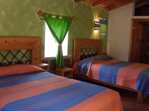 1 dormitorio con 2 camas y ventana en Villa Amacalli, en Tlalpujahua de Rayón