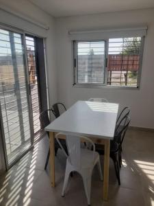 uma mesa branca e cadeiras num quarto com janelas em Alquiler Casa Guaymallen em Guaymallén