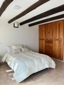 een slaapkamer met een wit bed en houten kasten bij Apartamento en Villa de Leyva in Villa de Leyva