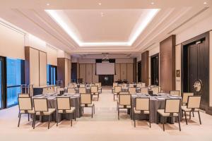 une salle de conférence avec des tables et des chaises et un écran de projection dans l'établissement Waldorf Astoria Doha West Bay, à Doha