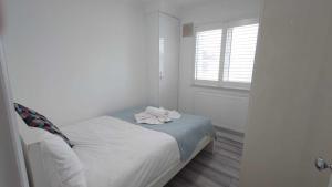 ein weißes Schlafzimmer mit einem Bett und einem Handtuch darauf in der Unterkunft Eurostar City Apartments in London