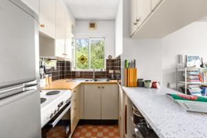 a kitchen with white cabinets and a window at Cosy Sydenham 1-Bed by Inner-West's Attractions in Sydney