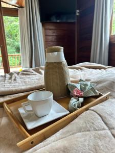 a tray with a plate and a vase on a bed at Chalé Girassol in Venda Nova do Imigrante