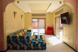 ein Wohnzimmer mit einem Sofa und einem TV in der Unterkunft Dar N'FIS in Lalla Takerkoust