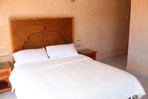 a white bed with a wooden headboard in a bedroom at Villa Piscine Privée Jaccuzi in Lalla Takerkoust