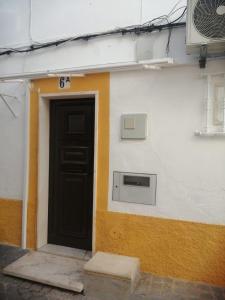 a building with a black door and a window at Casa da Romeira in Elvas