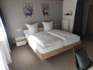 ein Schlafzimmer mit einem großen Bett mit weißer Bettwäsche in der Unterkunft Landhaus Weißer Hirsch in Füssen