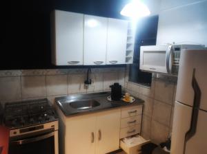 a small kitchen with a sink and a stove at Apartamento Parque Itaimbé - Centro - Garagem in Santa Maria